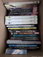 Stack of approximately thirty TPBs inside box showing spines including NYX, Age of X-Man, Damage Control, Clockwork Lives, Golden Compass, Lucifer