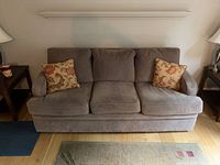 Front view of the taupe three-cushion sofa with two throw pillows