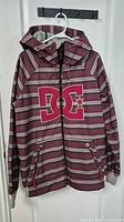Front view of striped DC softshell jacket on hanger