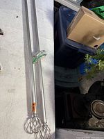 Two silver metal curtain rods with cage finials laid side by side, showing overall appearance