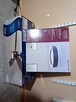 Both boxed lighting fixtures side by side: Harbor Breeze Stormont 42" ceiling fan and Home Decorators Collection 13" LED flush mount light