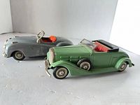 Gray Jaguar and green Cadillac tin toy cars side view
