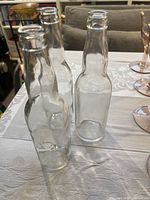 Three clear glass soda bottles standing on table