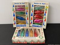 Three boxes of vintage glass ornaments showing contents and graphics
