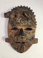 Front view of terracotta mask showing lizard motif and geometric carvings