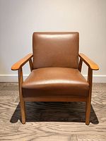 Front view of brown faux leather armchair, full chair visible