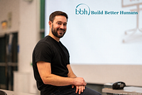 Consultant seated with Build Better Humans logo projected behind