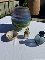 Group shot of all four items: multicolor glass vase, enamel perfume bottle, blue round bottle, painted ceramic bowl
