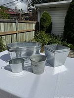 Group view of nested rectangular tubs, two small pails and a square planter