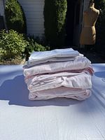 Stacked view of folded pink and white bedding pieces