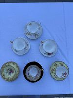 Five assorted teacup and saucer sets laid out on table