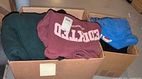 Two cartons filled with folded hoodies and sweatpants