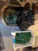 Two storage bins containing assorted artificial evergreen decor pieces