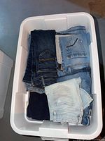 Stack of folded jeans in white bin showing assorted washes