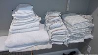 three stacks of assorted towels on shelf