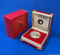 Coin displayed in red presentation case with outer sleeve and certificate