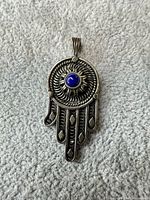 Front view of sterling silver Hamsa pendant showing blue cabochon and overall design