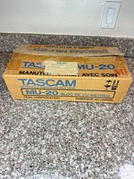 Closed cardboard box labeled Tascam MU-20