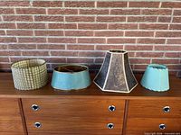 Four assorted vintage fibreglass lamp shades on sideboard