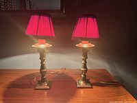 Both brass table lamps illuminated on wooden surface