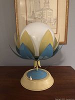 Front view showing globe, yellow and blue metal petals, and tiered base