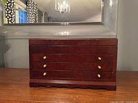 Front view showing three drawers and brass-tone knobs