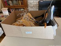 Cardboard box containing assortment of wooden and plastic hangers