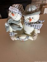 Front view of attached plush snowman pair showing scarves, hats, facial features, and overall condition