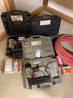 Overview of three Porter-Cable nailers/stapler in cases, fastener boxes, and coiled air hose