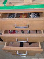 Three open drawers showing hand tools and screws