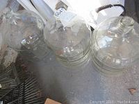 Three large clear glass wine fermenting casks placed on a concrete floor showing their shape and size.