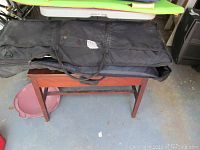 Roland EM-303 keyboard carrying case placed open on wooden bench in garage, black with zipper and handles.