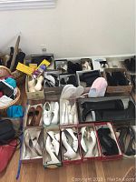 Wide view of assorted women's shoes in boxes and baskets including heels, boots, and slippers with some in shoe boxes and some loose