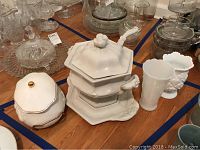White English ironstone tureen with ladle, hexagonal shape, flower detail on lid, ornate handles, hexagonal base.