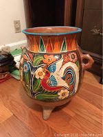 Hand-painted colorful clay pot on three legs, bird and floral motifs