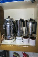 Photo showing Profito Stella steamer, two stainless steel espresso makers, and three coffee cups