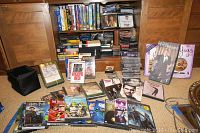 Wide view of collection showing DVDs, CDs and VHS tapes packed in shelves and boxes, with some titles displayed in front.