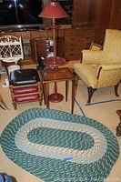 Photo showing a floor lamp, wooden side table with leather top, three stackable footstools, and some other furniture in the room.
