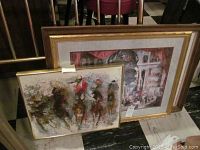 Two framed wall art prints leaning against a staircase railing, one original horse race painting by Barton and one architectural collage print.