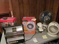 Overview of multiple heaters and fans including Artesia sun lamp, Holmes heater fan, Honeywell fan, metallic and small fans.
