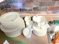 Stack of dinner plates, saucers, mugs and bowls on countertop
