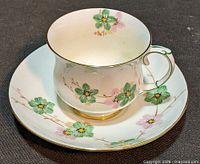 Teacup on saucer showing floral design and gold trim