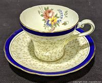 Teacup on saucer showing cobalt border, gold twig pattern and interior bouquet