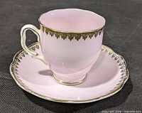 Pink demitasse cup on saucer showing color, gilt trim and overall condition