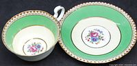 Top view of cup interior and saucer showing green band, gold trim, floral centers