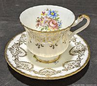 Teacup on saucer showing overall design, floral interior, gold filigree