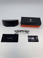 All items in lot: eyeglasses, hard case, outer box, cloth, card