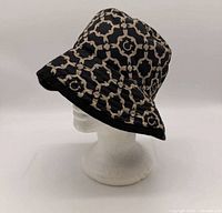 Left side view of the bucket hat showing exterior monogram pattern and brim shape