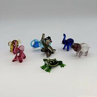Group shot showing all seven multicolor glass animal figurines