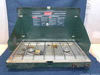 Open stove showing burners, grate, knobs, lid